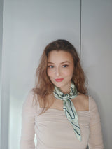 Kvinde iført LA SUIT Pistachio Silketørklæde bundet rundt om halsen.