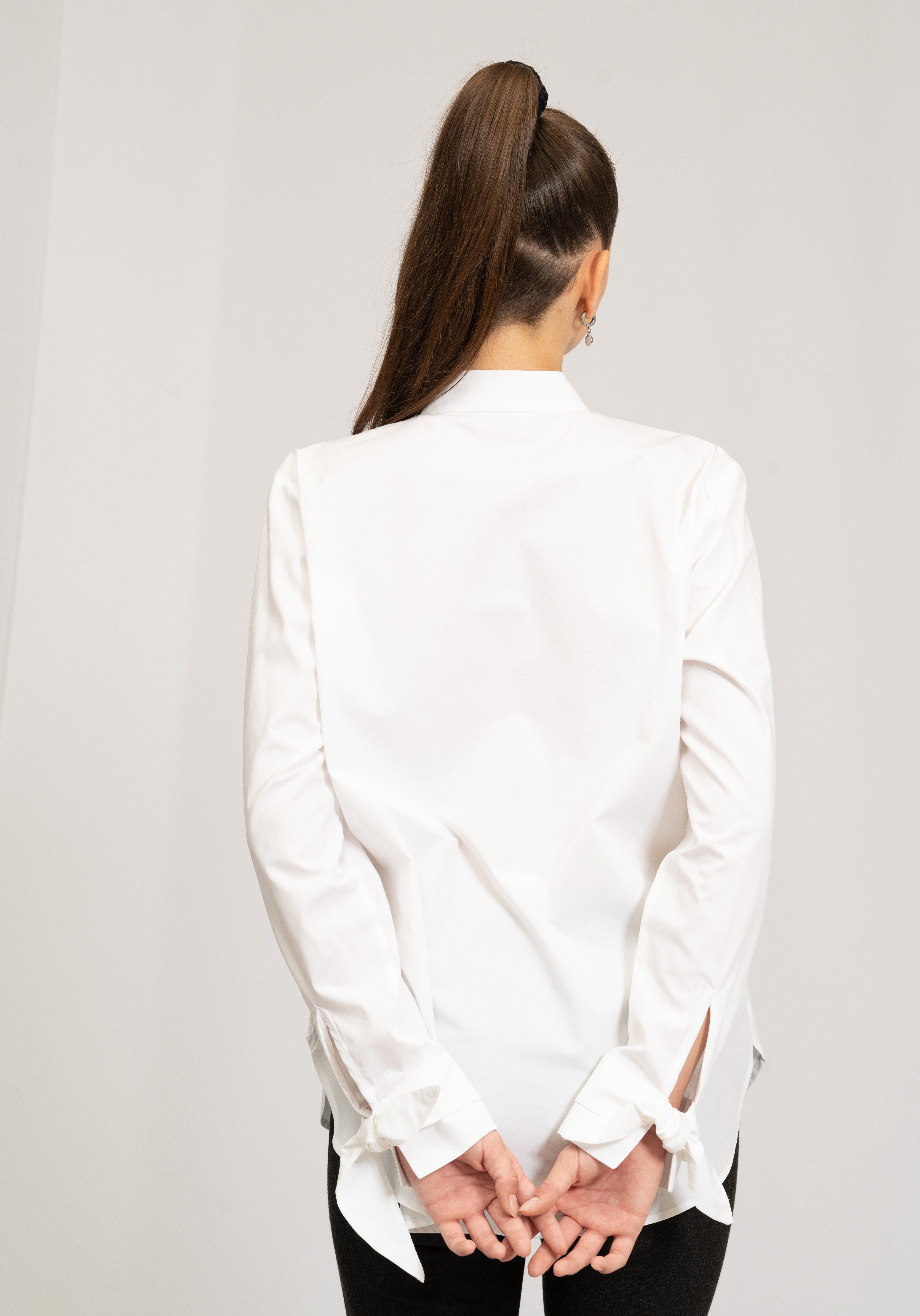 Hvid skjorte med moderne detaljer, heriblandt sløjfer på manchet.